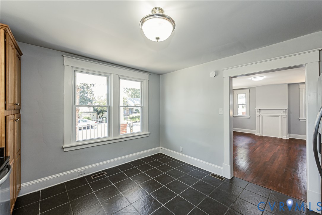 Tile flooring, built-in wooden cabinetry, double-hung windows with wide casing, and classic overhead lighting fixtures
