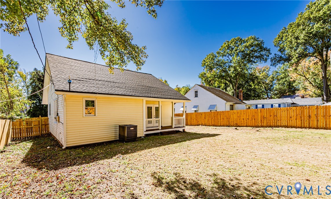 Exterior view featuring vinyl siding, an asphalt shingle roof, double entry doors, a covered porch, and wood privacy fencing
