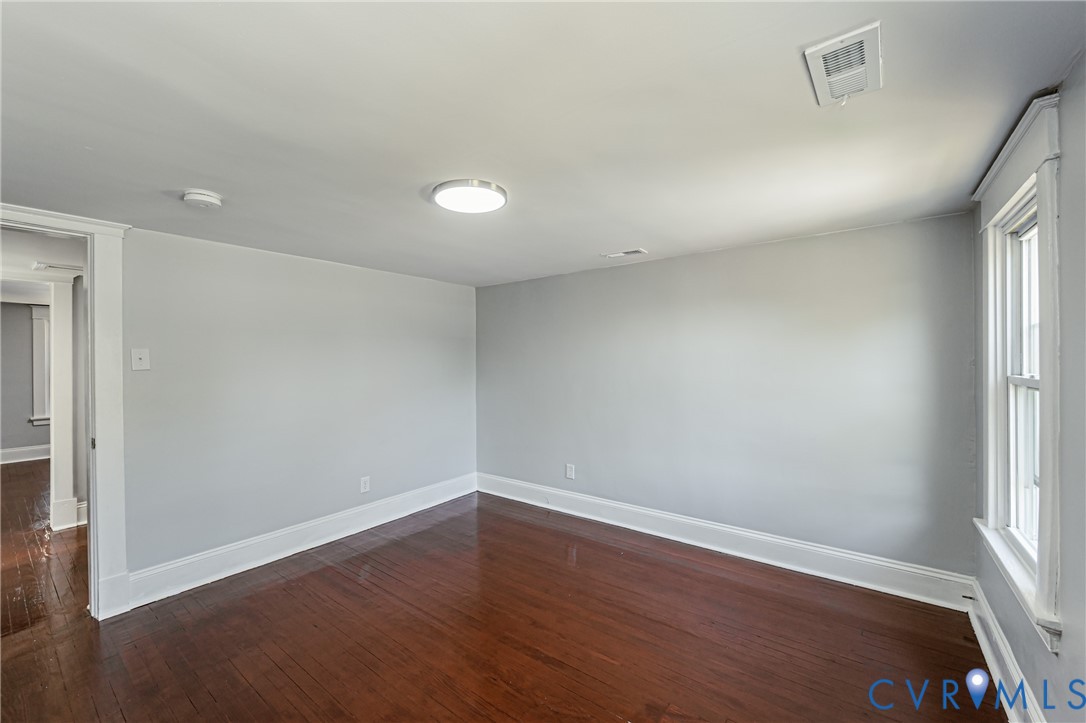 Interior room featuring wood-finish flooring, neutral wall paint, and a single-hung window with wide casing