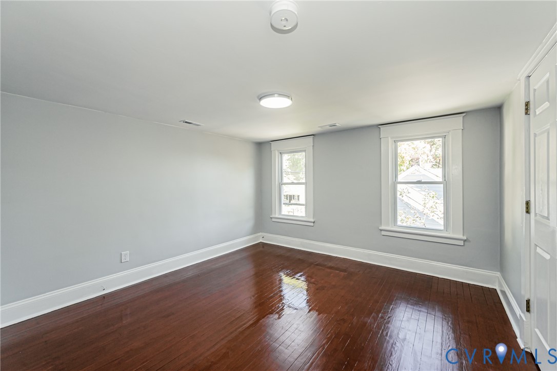 Room featuring wood-finish flooring, two double-hung windows with white trim, and ceiling-mounted lighting