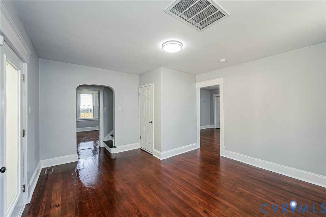 Interior space featuring wood-finish flooring, an arched entryway, and a multi-panel door