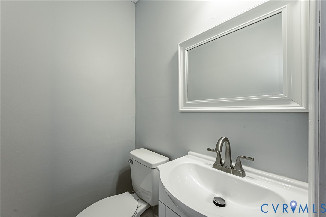 Vanity featuring an integrated white sink, brushed nickel dual-handle faucet, rectangular framed wall mirror, and porcelain toilet