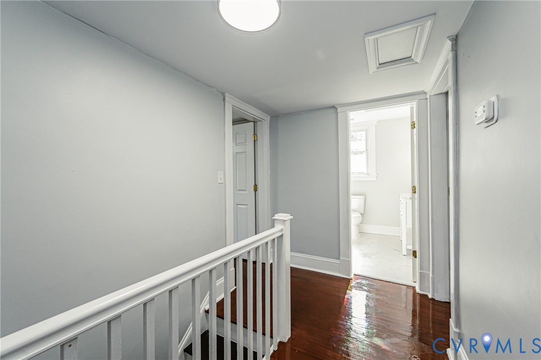 Hallway featuring polished wood-finish flooring, white wood railing, six-panel interior doors, and a flush-mount overhead light fixture