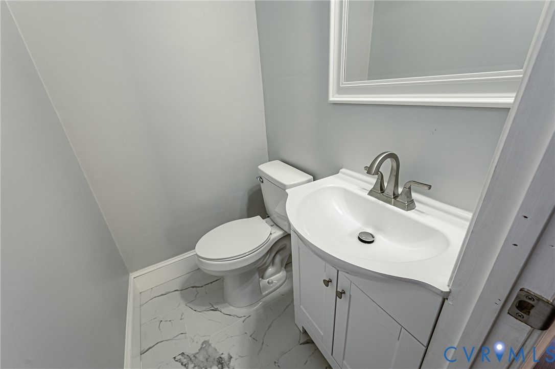 Bathroom featuring a white vanity cabinet with an integrated sink, brushed nickel faucet, wall-mounted mirror, and tile flooring