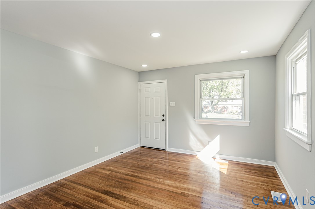 Interior space featuring light-toned neutral walls, wood-finish flooring, recessed lighting, and white-trimmed windows