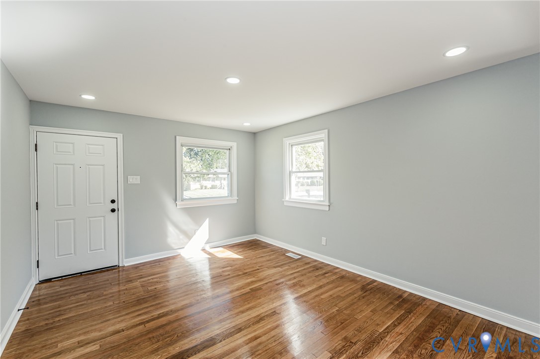Wood-finish flooring, recessed lighting, neutral wall paint, and two double-hung windows
