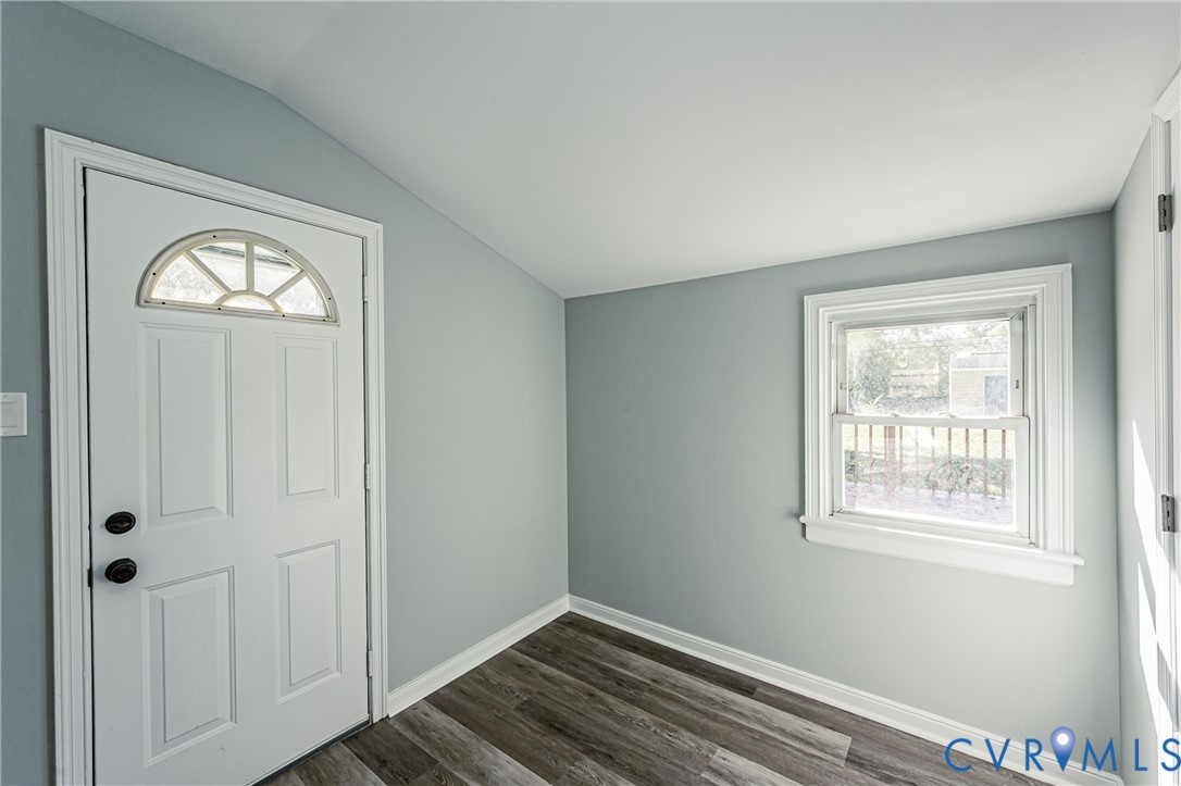 Interior room featuring wood-finish flooring, vaulted ceilings, and a single-hung window with casing