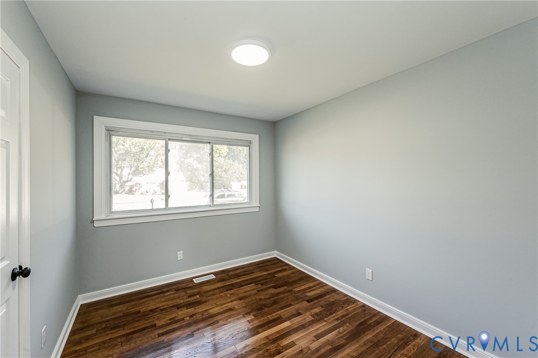 Interior space featuring wood-finish flooring, neutral wall tones, a large slider window, and a flush-mount ceiling light fixture