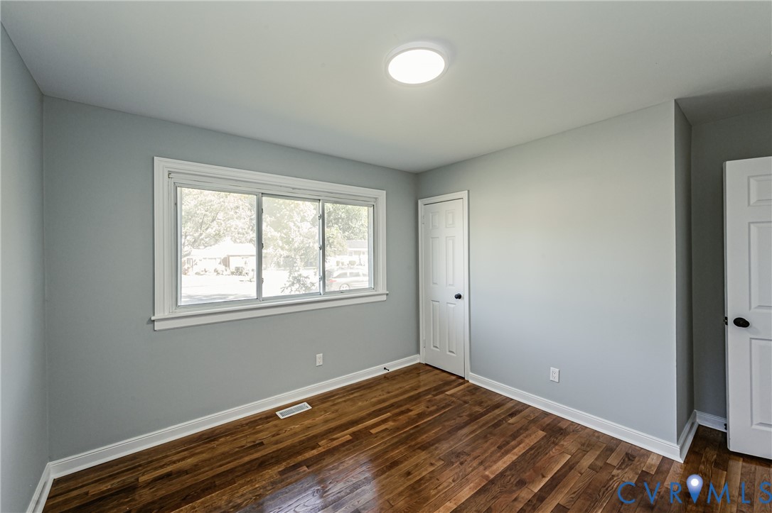 Neutral-toned interior featuring wood-finish flooring, a large window with white trim, and two paneled interior doors