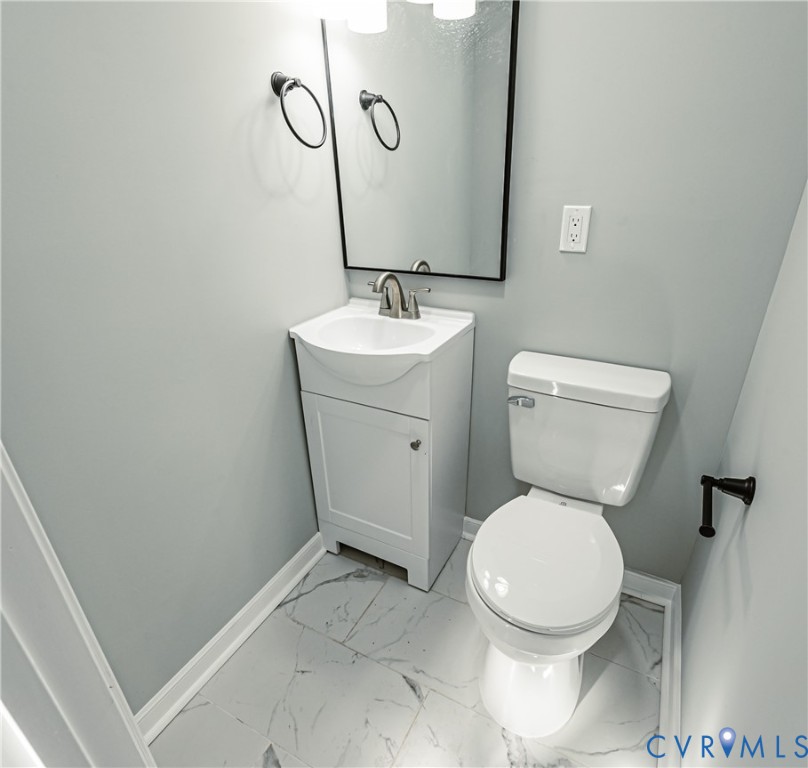 Compact vanity with a white integrated sink, polished metal faucet, wall-mounted rectangular mirror, and large-format tile flooring
