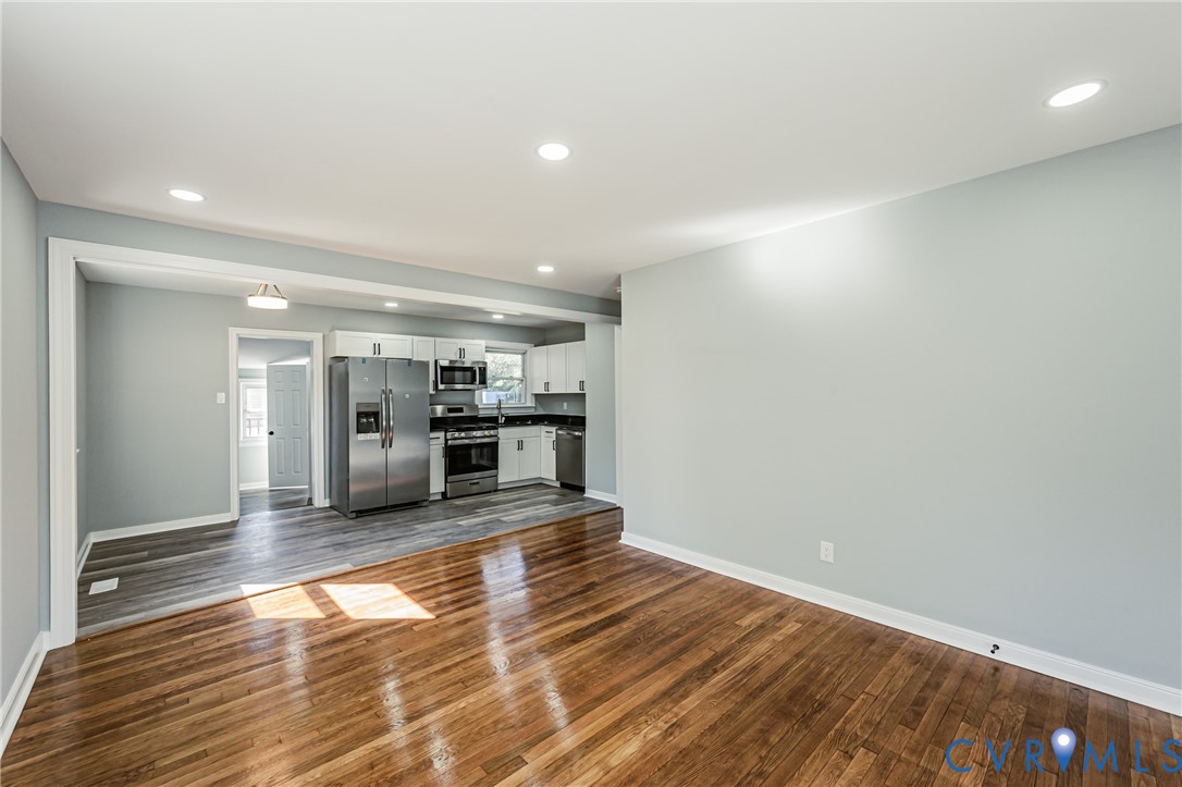 Hardwood flooring, recessed lighting, and kitchen area featuring stainless steel appliances and wood-finish flooring