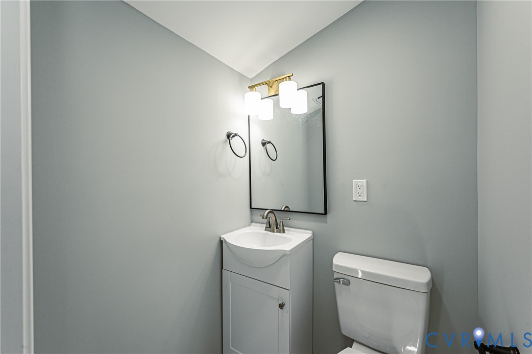 Pedestal-style vanity with integrated sink, rectangular wall mirror with black frame, three-light vanity fixture with globe shades, and polished metal hardware