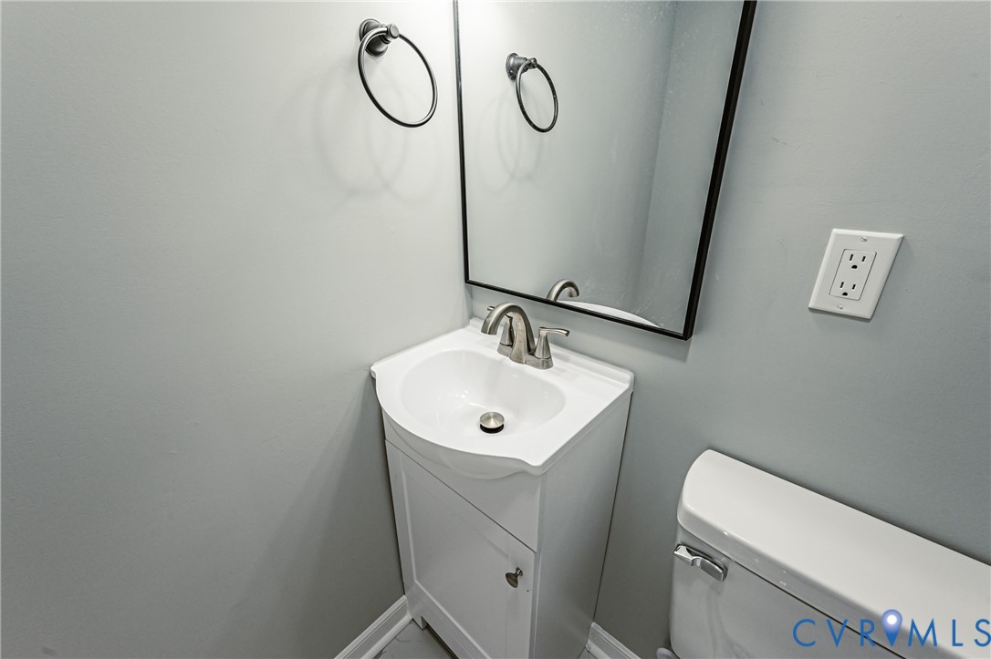 Pedestal vanity with white cabinetry and integrated basin, chrome finish faucet, black-framed mirror, and circular towel ring