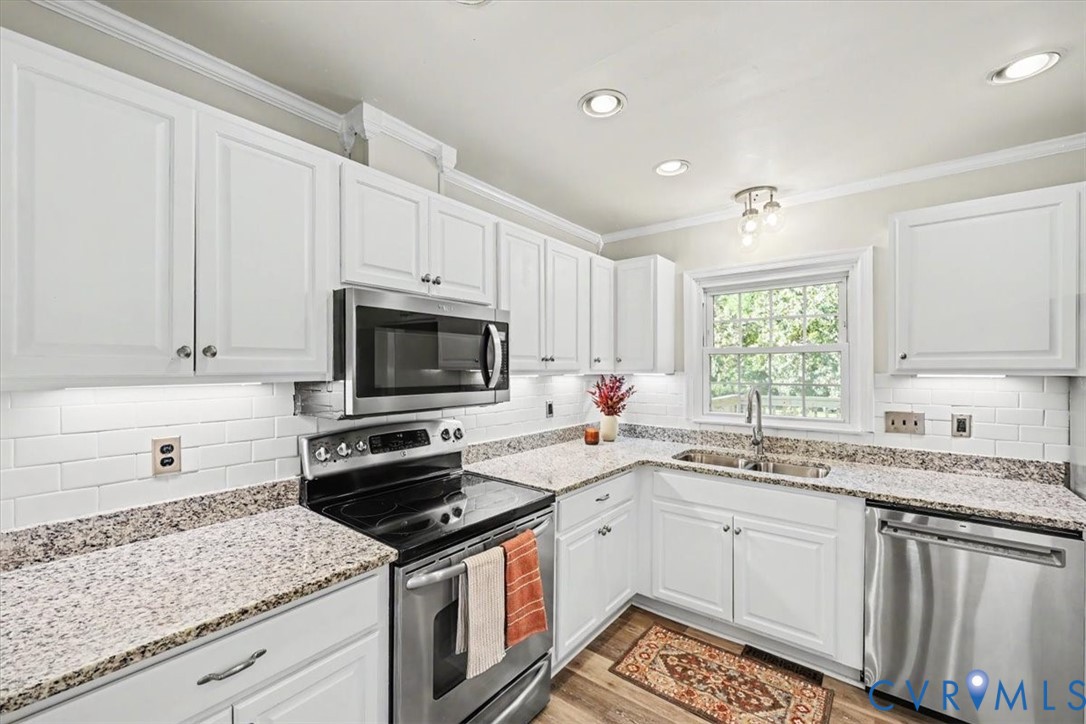 Kitchen featuring white shaker-style cabinetry, stone-finish countertops, subway tile backsplash, stainless steel appliances, and recessed lighting