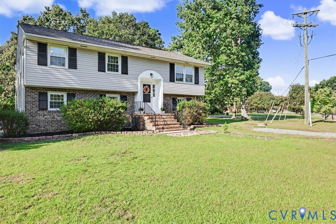Split-level exterior featuring brick and horizontal siding, arched entryway, brick-stepped stairs with metal railings, and multi-pane windows with decorative shutters Split-level exterior featuring brick and horizontal siding, arched entryway, brick-stepped stairs with metal railings, and multi-pane windows with decorative shutters