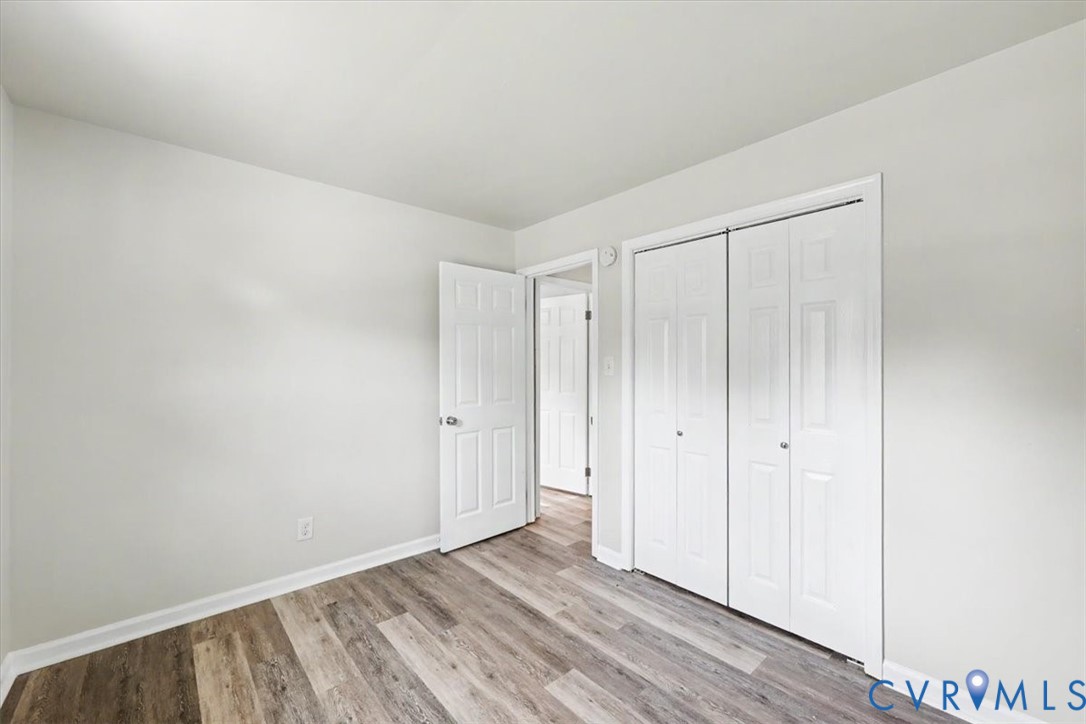 Neutral-toned interior space featuring wood-finish flooring, dual-panel interior doors, and a double-door closet with paneled detailing