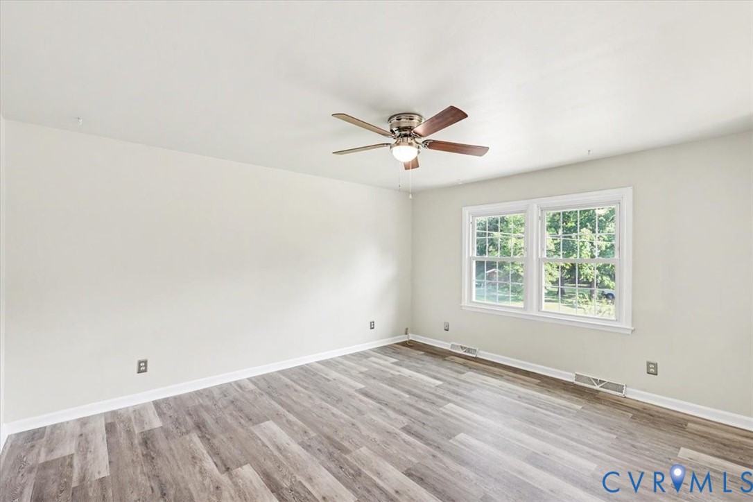 Room featuring wood-finish flooring, neutral wall paint, and a ceiling fan with integrated lighting