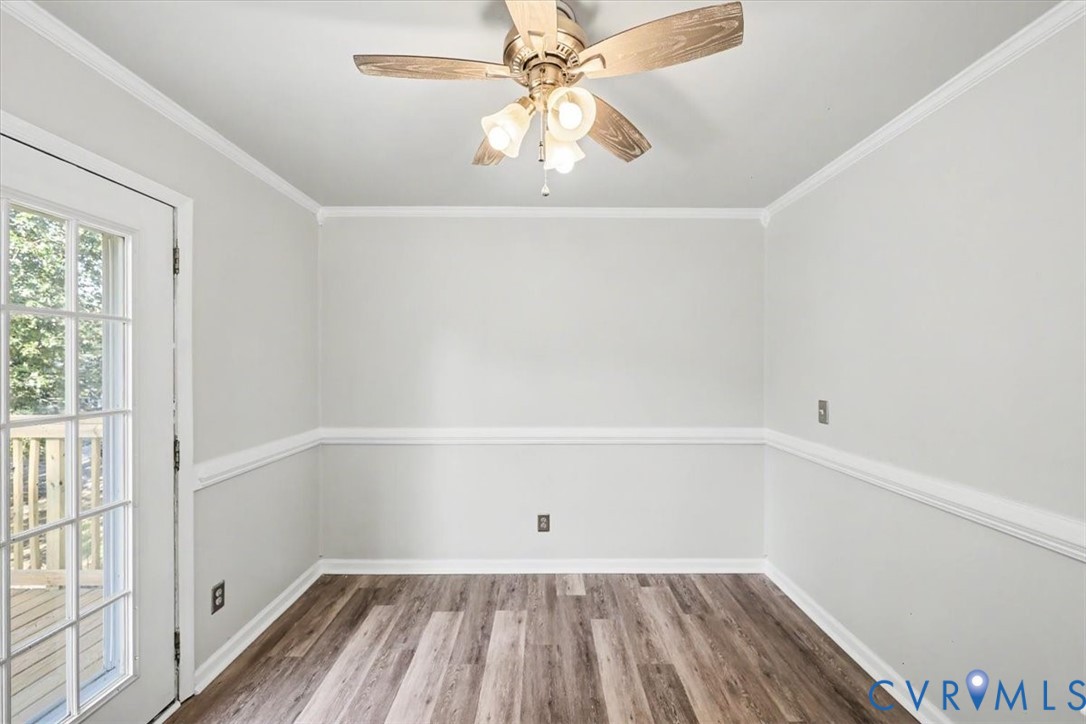 Interior space featuring wood-finish flooring, chair rail molding, a glass-paneled exterior door, and a three-light ceiling fan