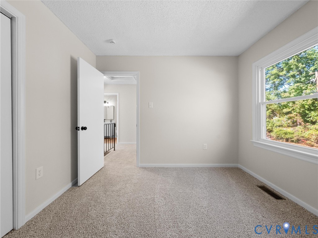 Neutral interior featuring wall-to-wall carpeting, a multi-pane window, and white interior doors with matte black hardware