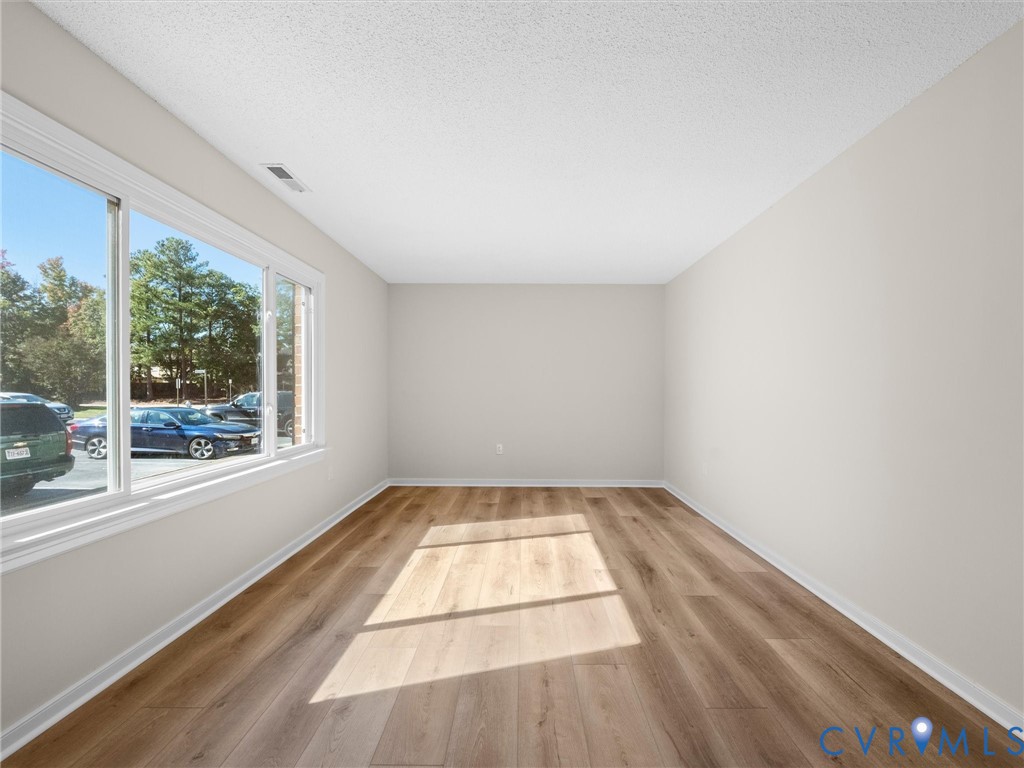 Interior room featuring wood-finish flooring, neutral wall tones, and a large horizontal window