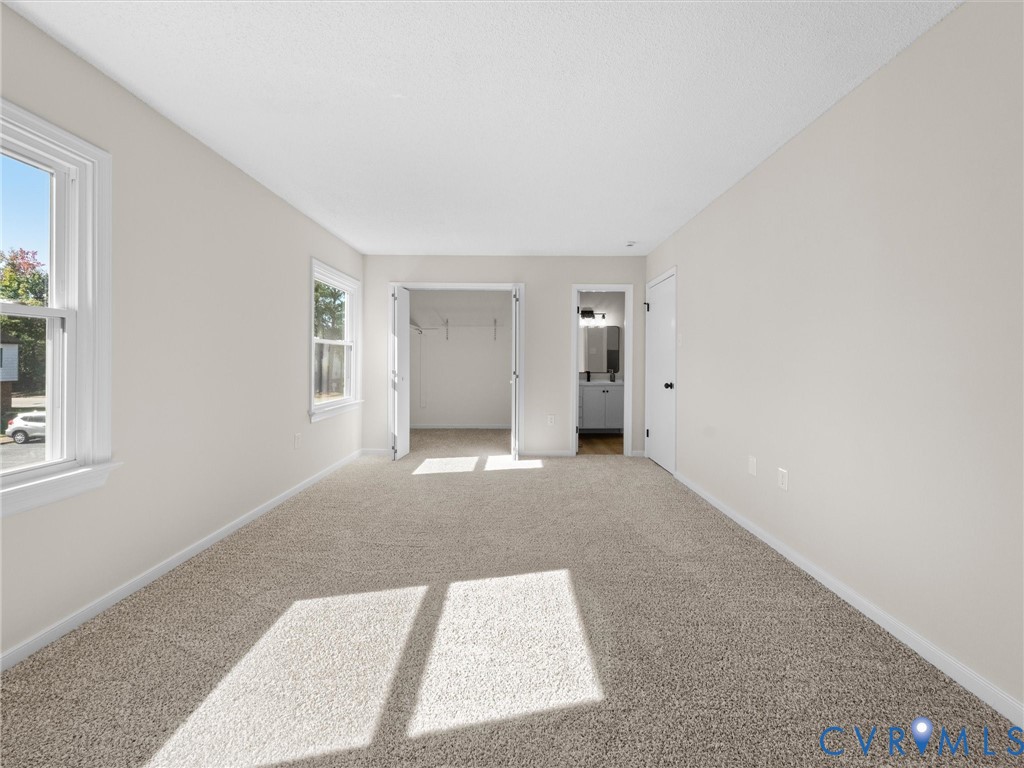 Neutral-toned interior space featuring wall-to-wall carpeting, dual-pane windows, a reach-in closet with double doors, and a solid-core interior door