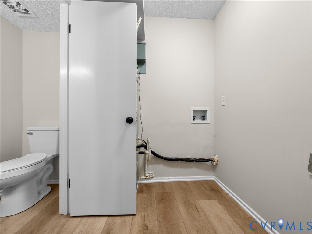 Ceramic toilet, wood-finish flooring, and recessed laundry hookups
