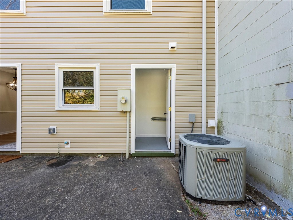 Exterior elevation featuring light-colored horizontal siding, single-hung window, dedicated outdoor storage entry, and exterior HVAC condenser unit