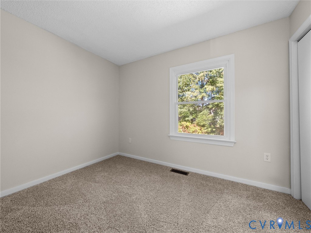 Neutral-toned interior space featuring wall-to-wall carpeting, a single-pane window with white casing, and a sliding closet door
