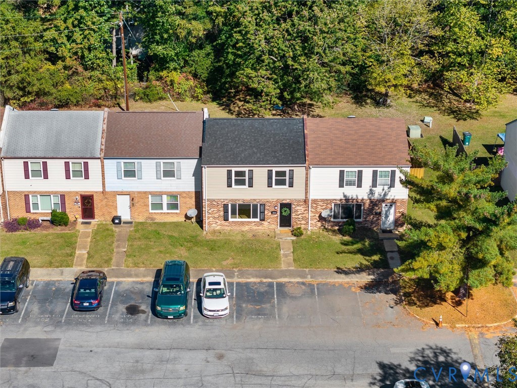 Multi-level townhouse exterior featuring a combination brick and siding facade, asphalt shingle roofing, and dedicated surface parking