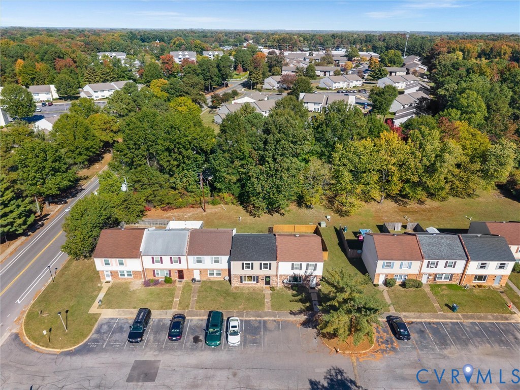 Aerial perspective featuring multi-story residential structures with gabled rooflines, brick facades, paved surface parking, and manicured grounds