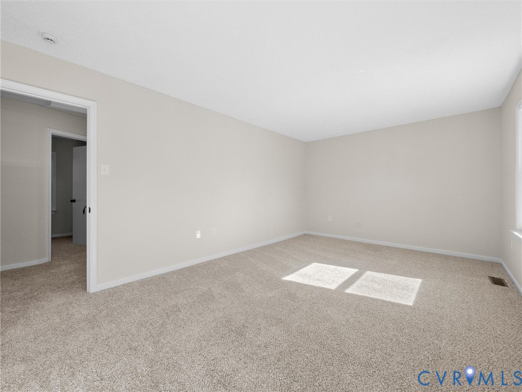 Neutral-toned interior space featuring light-colored wall paint and wall-to-wall carpeting