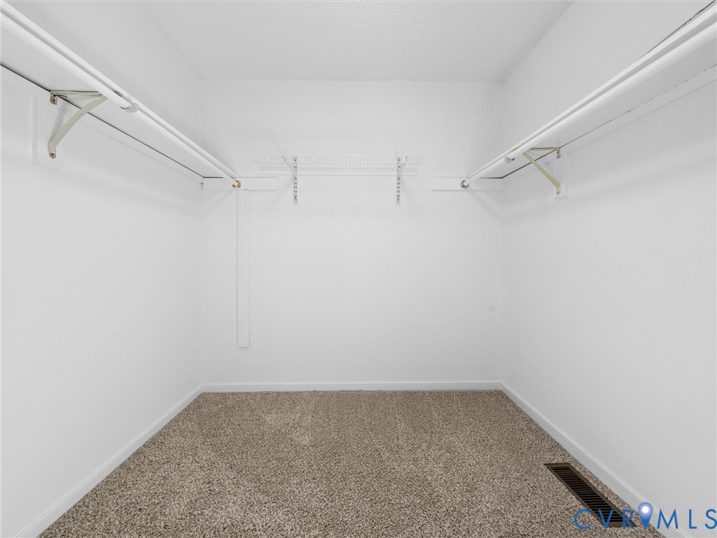 Walk-in closet featuring neutral carpeting, white walls, and dual-level wire shelving