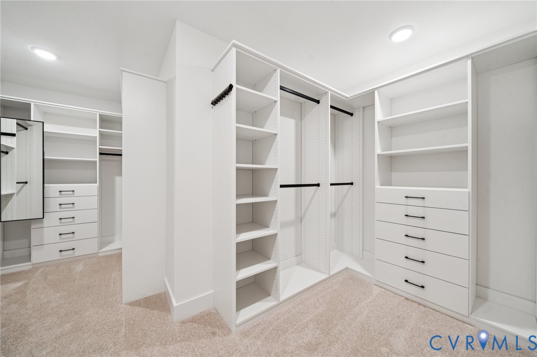 Custom walk-in closet featuring white built-in shelving, adjustable hanging rods, integrated drawer stacks, and matte black hardware