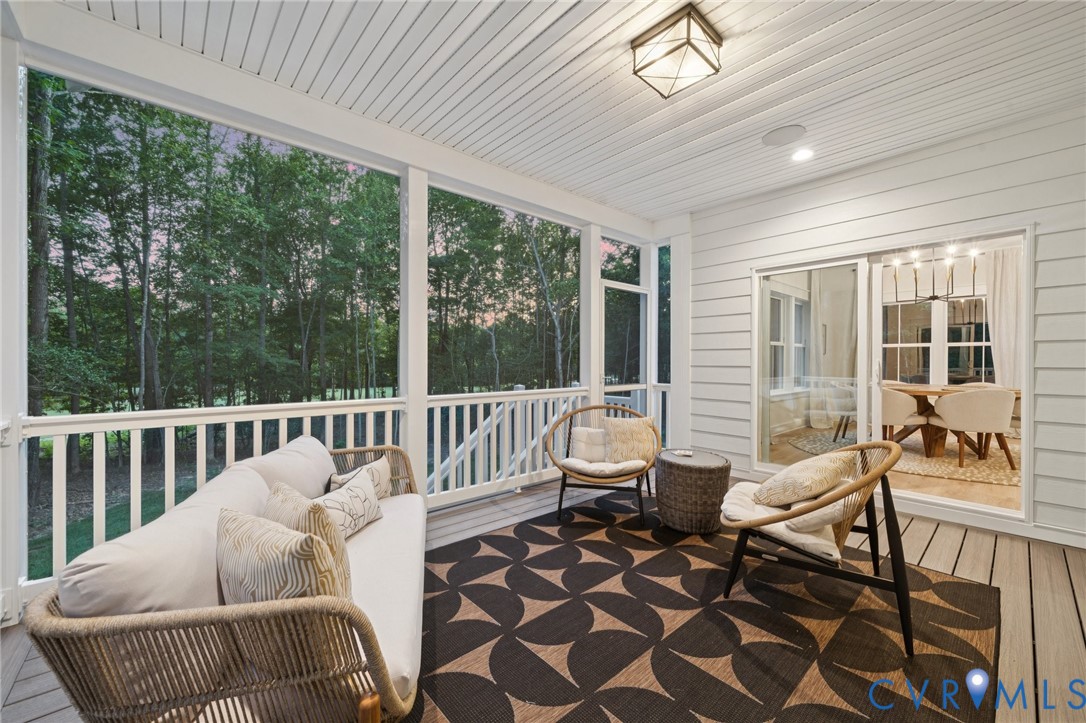 Screened-in porch featuring wood-finish decking, white horizontal siding, a beadboard ceiling, and a geometric-framed flush-mount light fixture