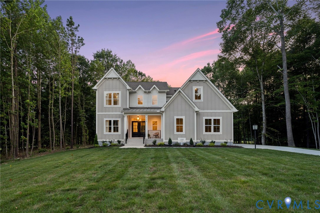 Two-story exterior featuring light-toned vertical siding, a covered front entryway with metal roofing accents, multiple gables, and multi-pane windows Two-story exterior featuring light-toned vertical siding, a covered front entryway with metal roofing accents, multiple gables, and multi-pane windows