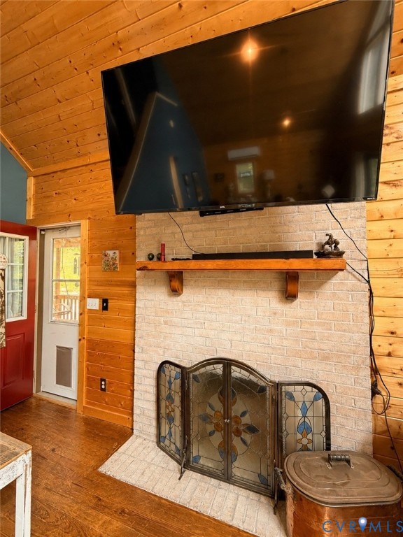 Tongue-and-groove wood wall paneling, light-toned brick fireplace surround, natural wood mantel, and wood-finish flooring