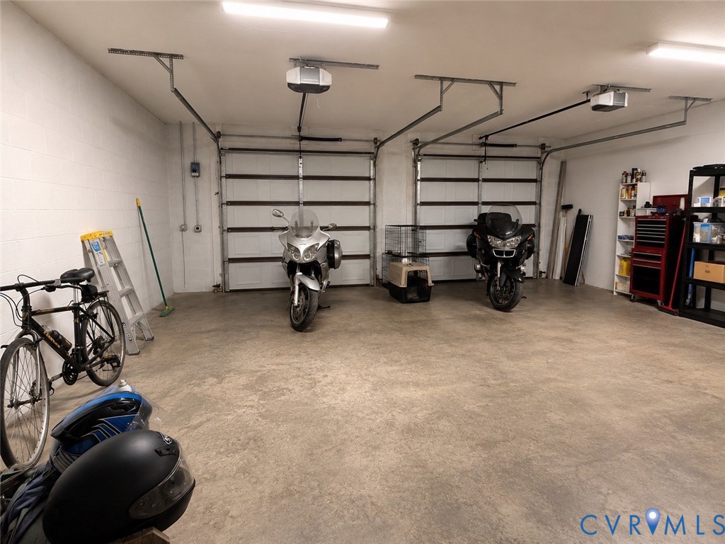 Two-car garage featuring concrete flooring, dual overhead automatic door openers, and fluorescent lighting