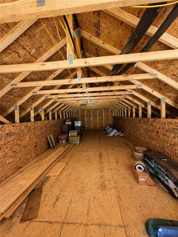 Unfinished attic space featuring exposed wood-truss framing, oriented strand board walls, and plywood subflooring