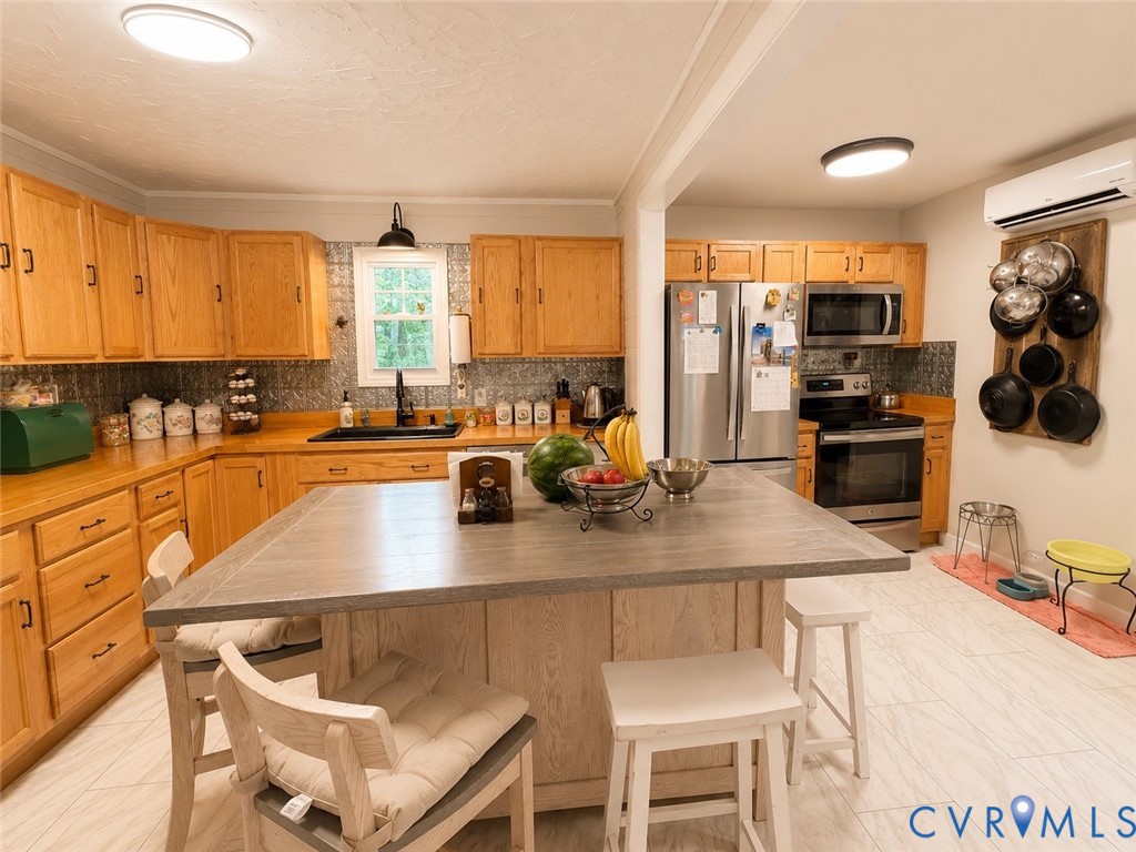 Kitchen featuring wood cabinetry, stainless steel appliances, central island with a grey composite countertop, patterned backsplash, and tile flooring