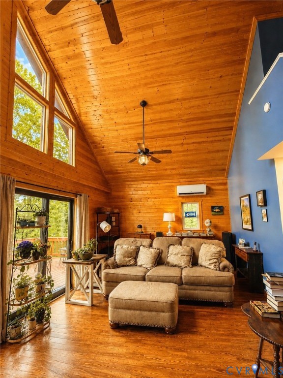 Vaulted ceilings with exposed natural wood paneling, wood-finish flooring, multi-pane floor-to-ceiling windows, and a wall-mounted ductless heating and cooling unit