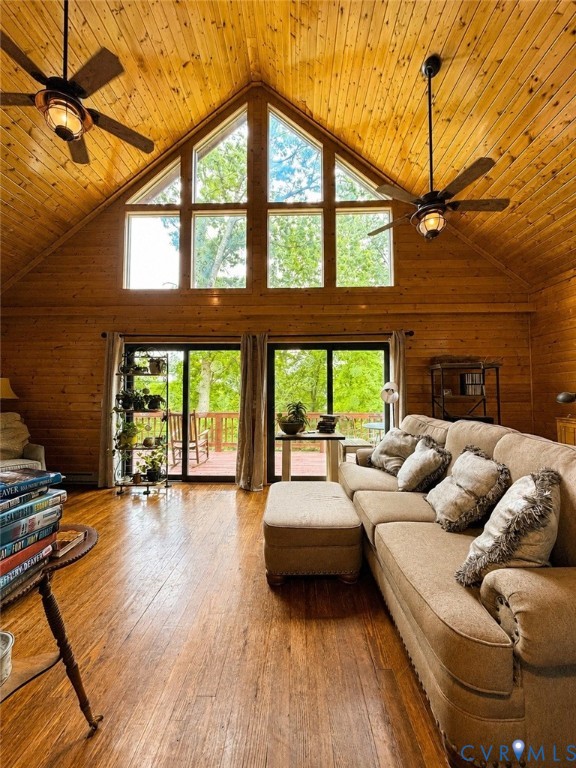 Vaulted ceilings with exposed wood paneling, floor-to-ceiling geometric windows, wood-finish flooring, dual ceiling fans, and sliding glass doors