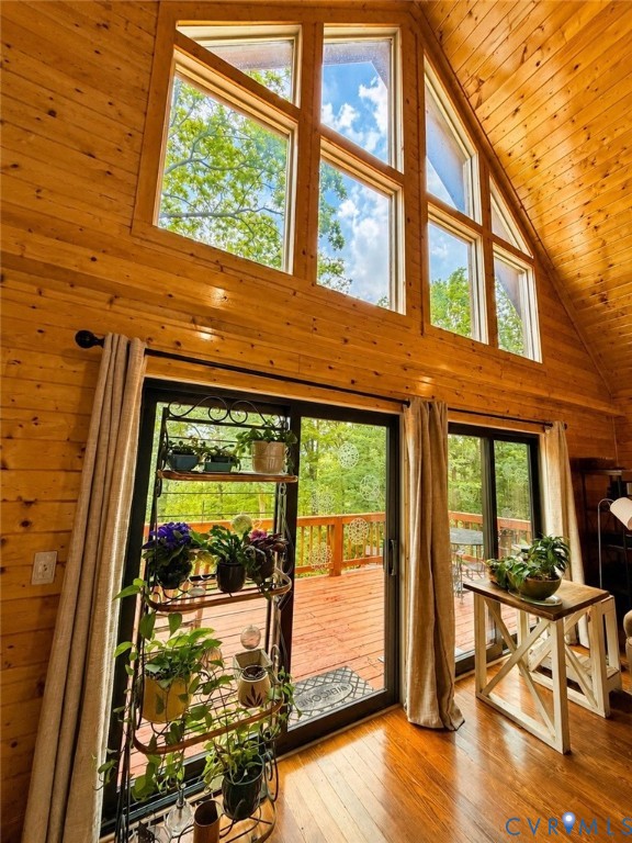 Vaulted wood-paneled ceiling, large multi-pane windows, and sliding glass doors opening onto a wooden deck