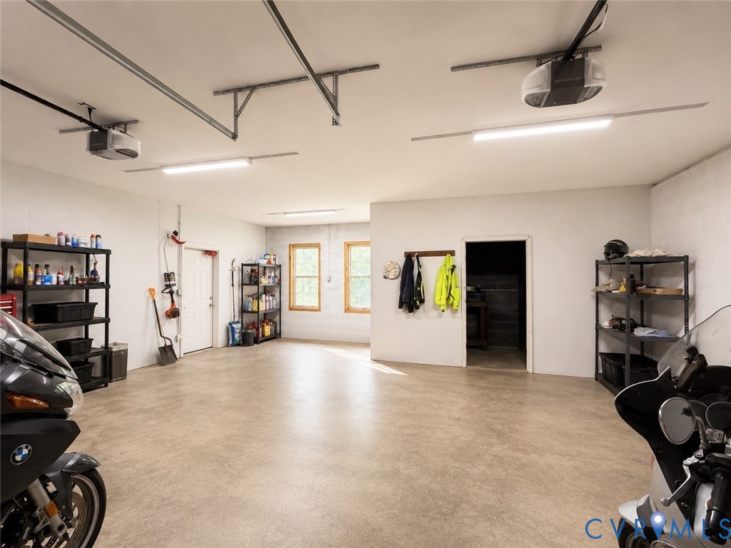 Spacious multi-car garage featuring textured concrete flooring, dual automatic garage door openers, energy-efficient LED lighting, and double-pane windows