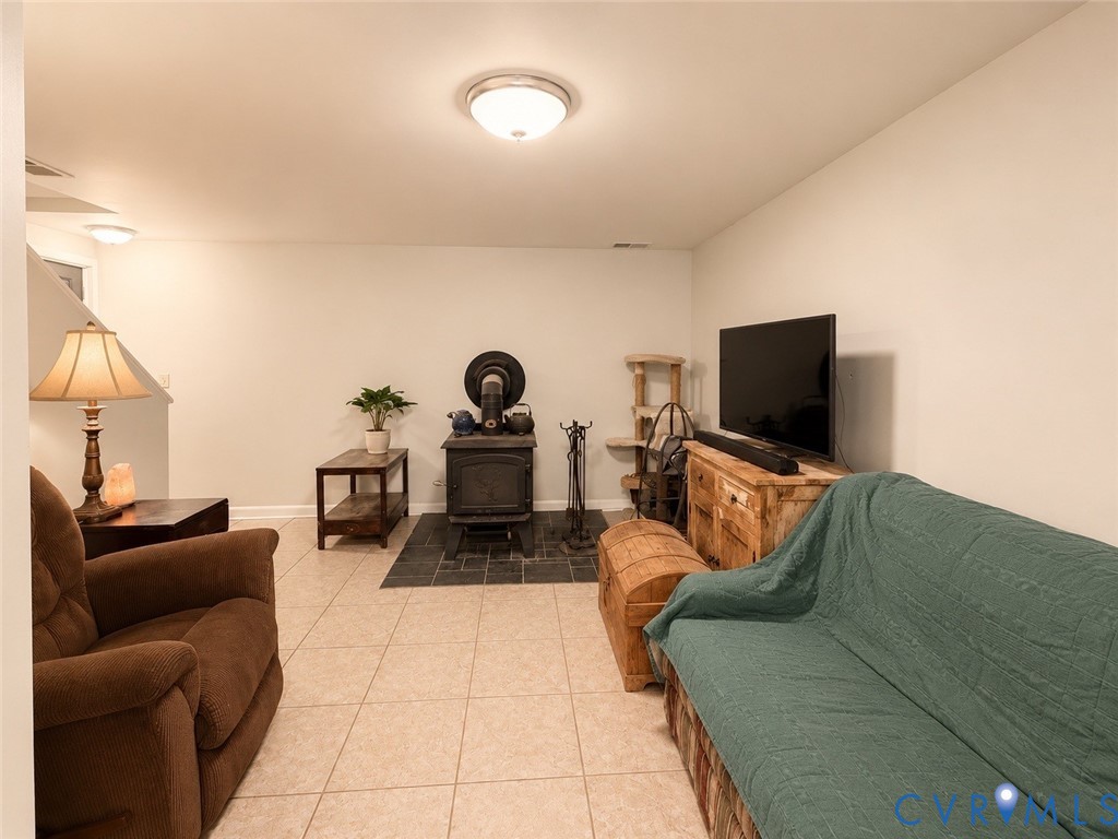 Interior space featuring neutral tile flooring, a cast-iron wood-burning stove, and a decorative slate tile hearth