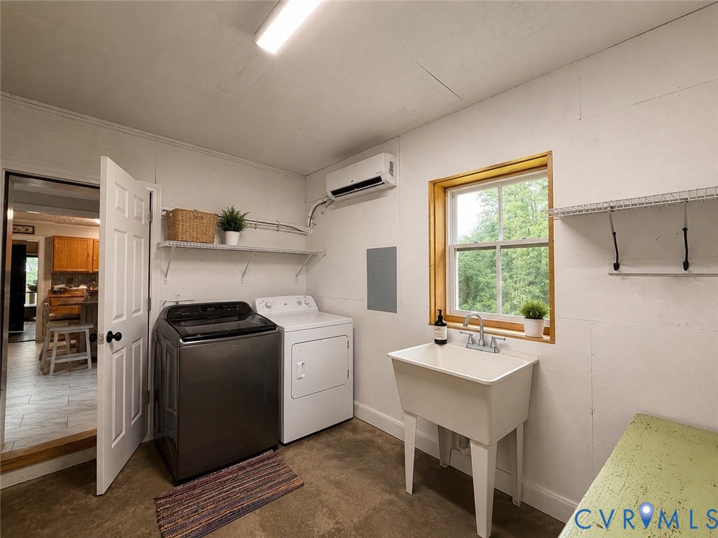 Laundry area featuring a utility sink with dual-handle faucet, wall-mounted ductless air conditioning unit, window with natural wood trim, and metal shelving