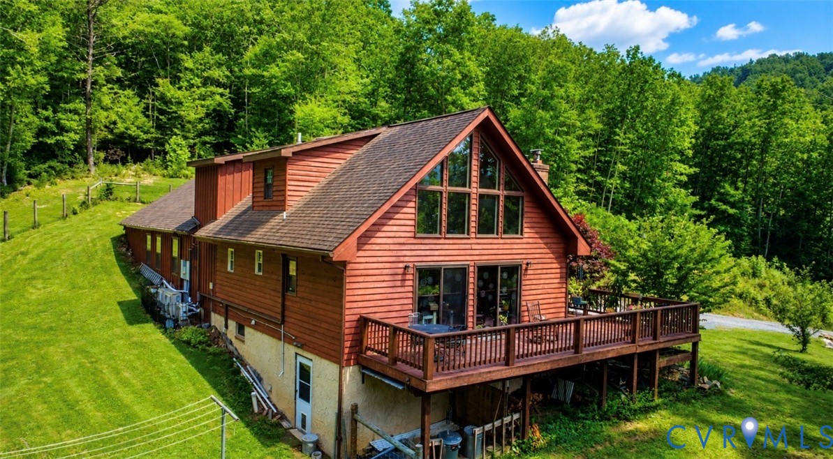 Multi-level wood siding exterior featuring a gabled roofline, expansive elevated deck with wooden railing, and floor-to-ceiling windows