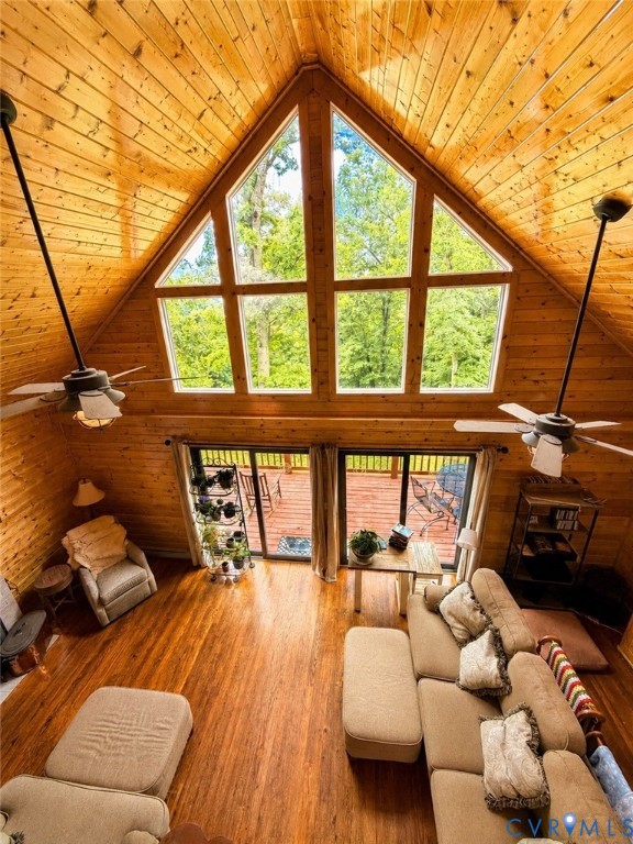 Vaulted tongue-and-groove wood ceiling, expansive floor-to-ceiling multi-pane window, wood-finish flooring, and dual ceiling fans
