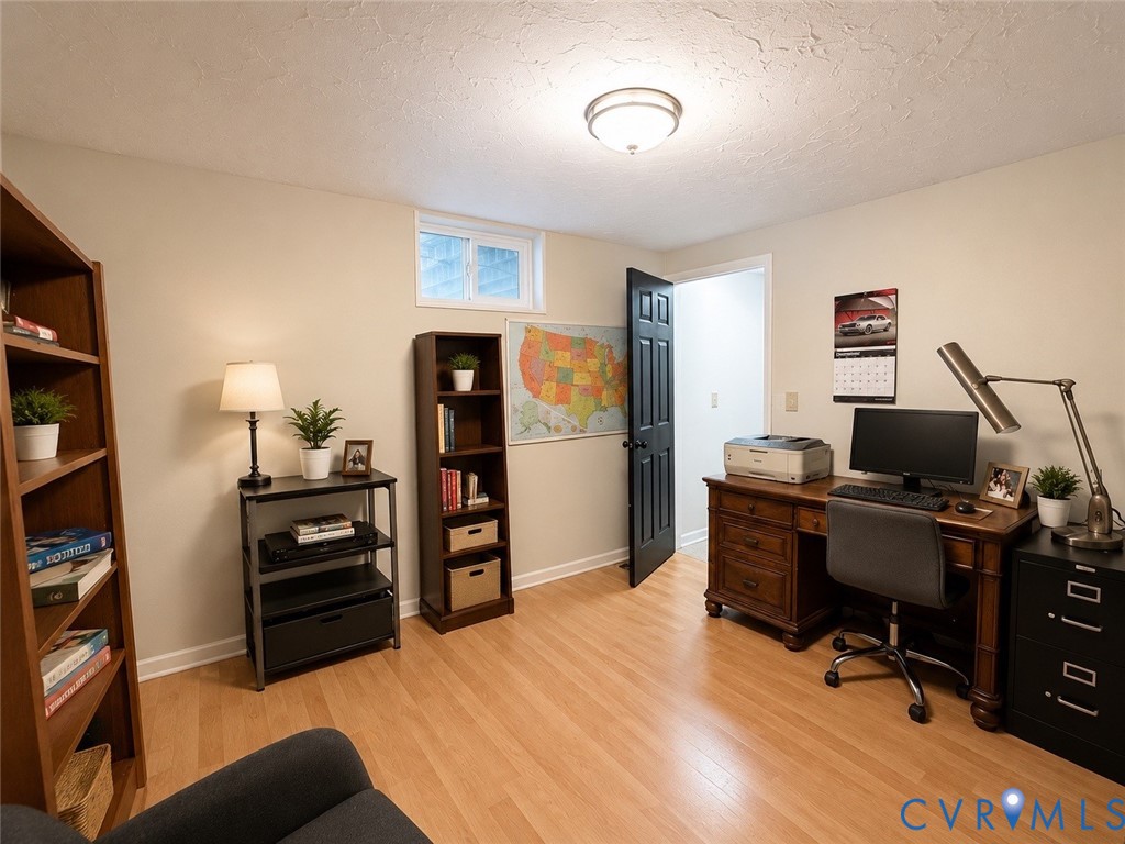 Room featuring wood-finish flooring, a recessed window, and a dark-finished interior door with coordinating hardware, illuminated by a ceiling-mounted flush light fixture
