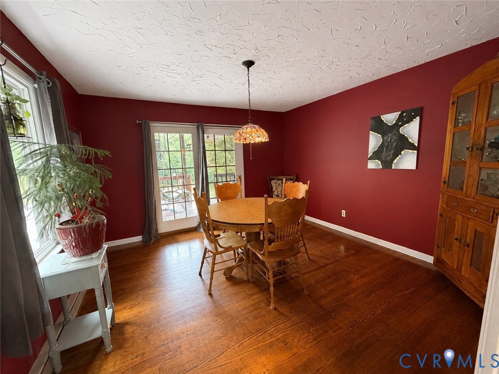 Dining area featuring wood-finish flooring, glass-paned double doors, a built-in wood china cabinet, and a multi-faceted stained-glass pendant light
