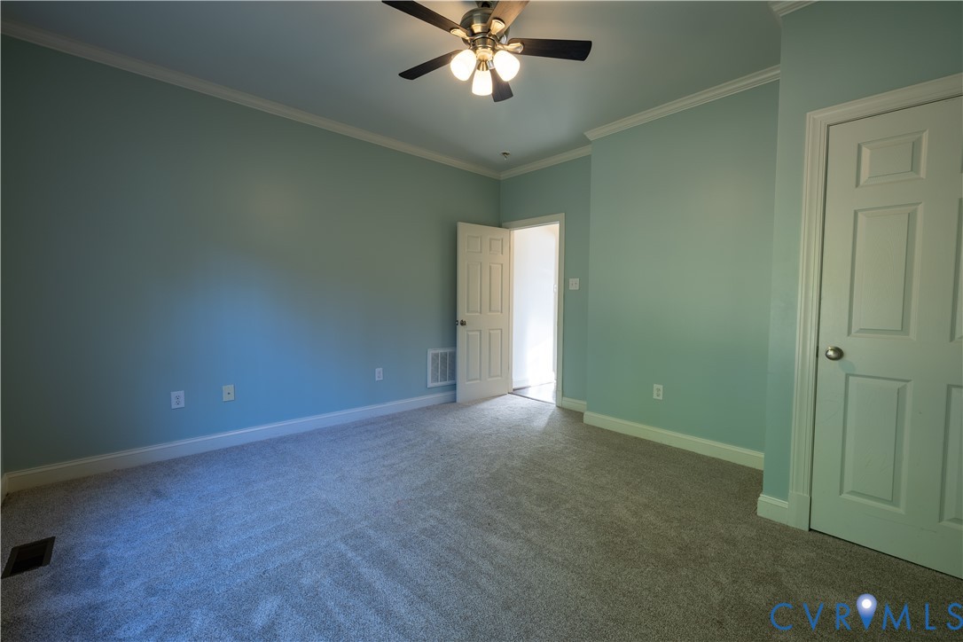 Room featuring neutral carpeting, a multi-light ceiling fan, and a solid-core interior door